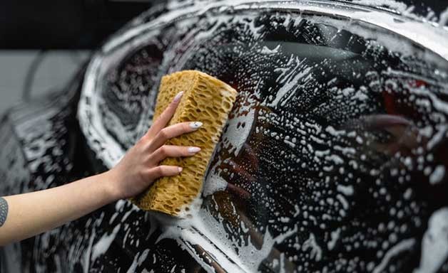 washing black car with sponge and soap