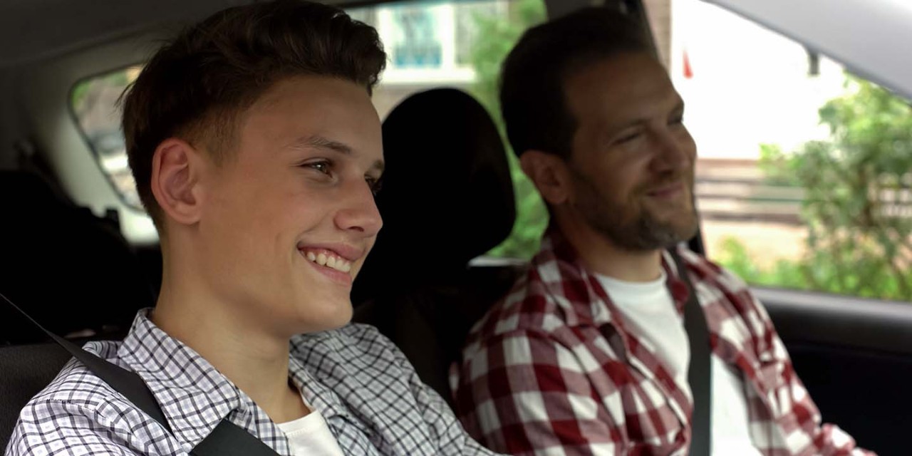  young man and his dad during driving lesson in a car