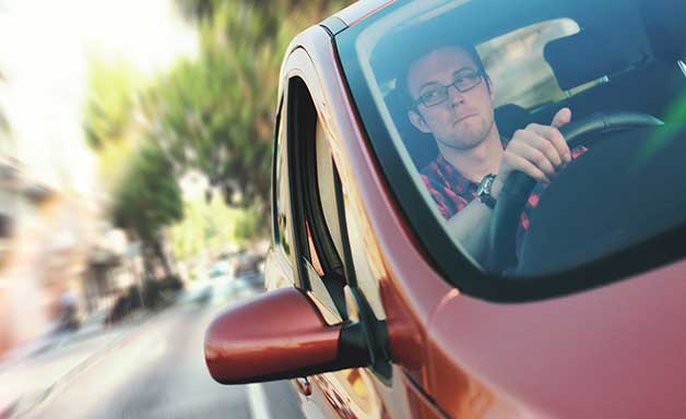  young man looking at side view mirror while driving car