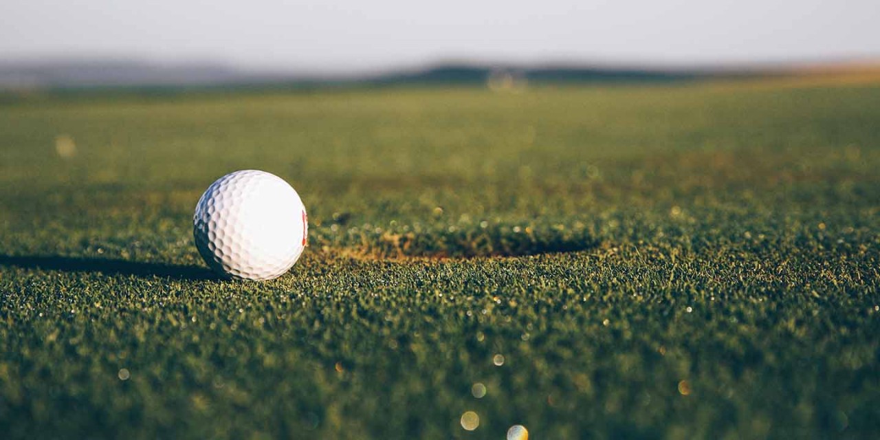  Ground level close up of golf ball close to hole 