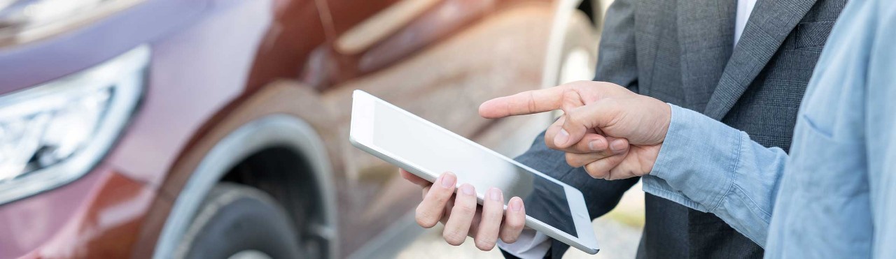  People with a tablet in front of  a car