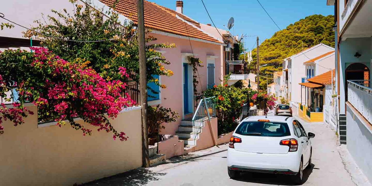 A street scene with a white car driving on a street in the traditional village