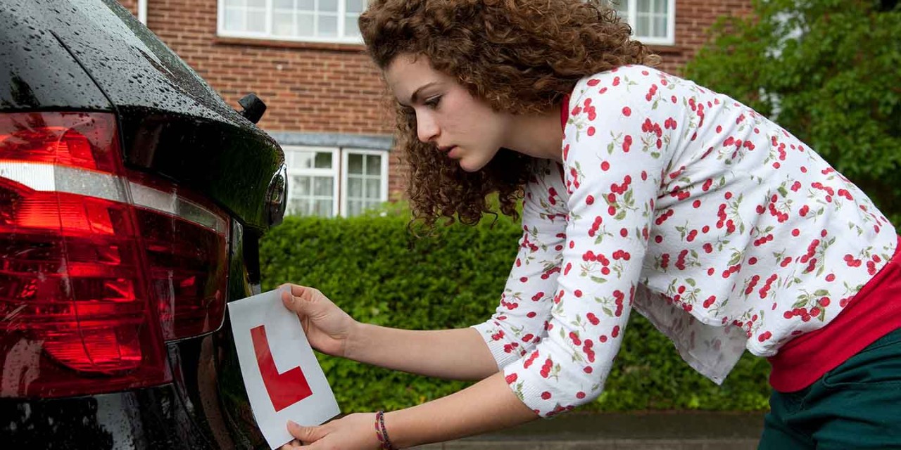 woman attaches L plate on the car