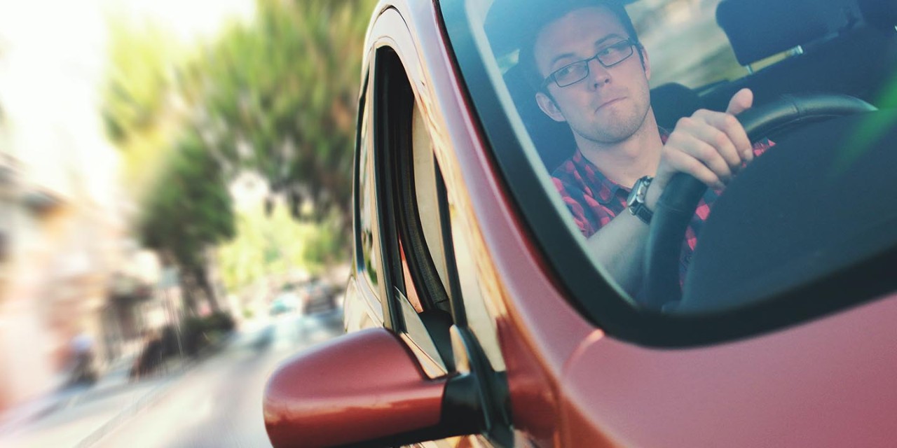 young man driving and looking the mirror