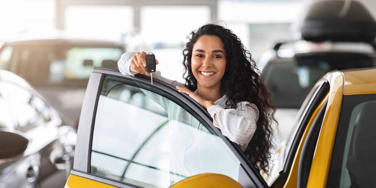 smiling young woman with a car key on hand 