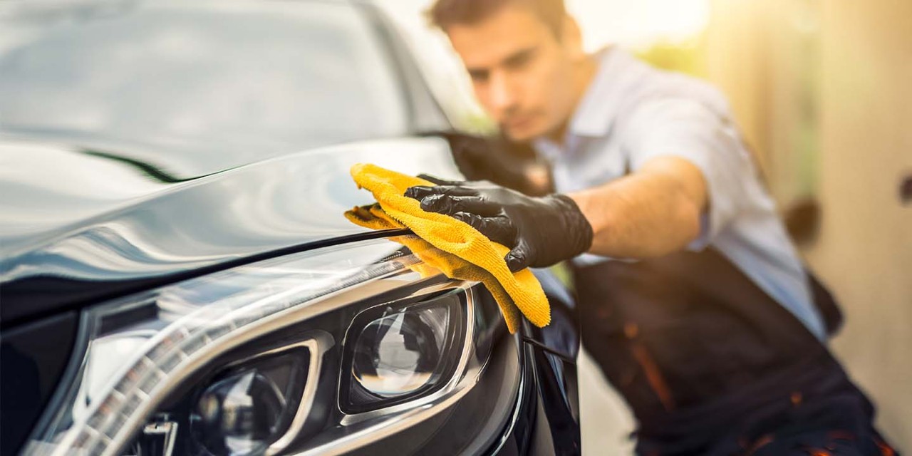 man holds the microfiber in hand and polishes the car