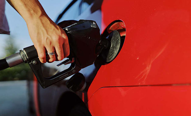 a person pumping gasoline fuel in car at gas station