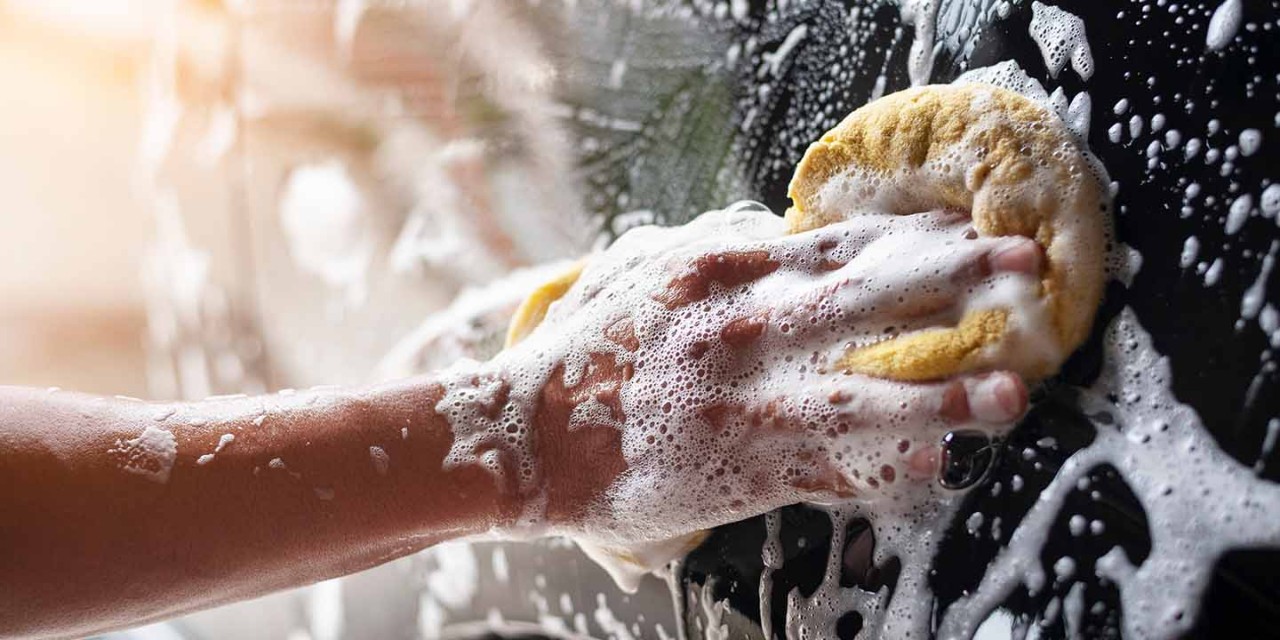  a hand washing a black car with a sponge 