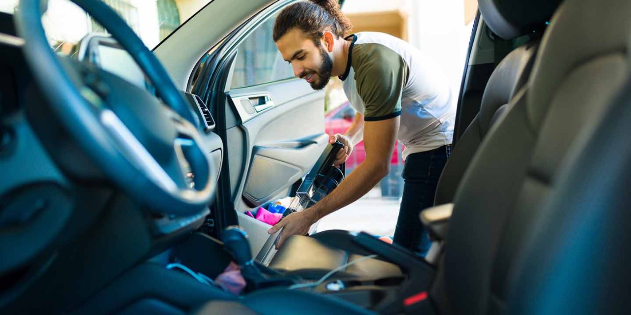 man cleaning inside car with vacuum 