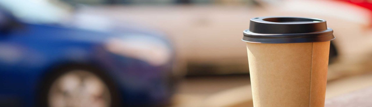  Coffee cup on a bench in front of a car