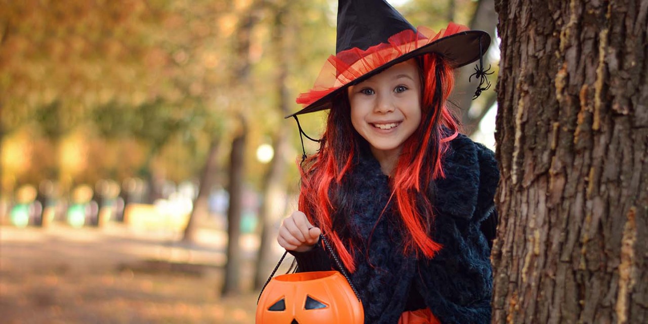 Little girl smiling and carrying pumpkin bucket