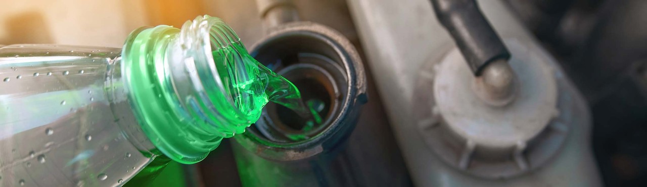 Green coolant pour from plastic bottle into car radiator
