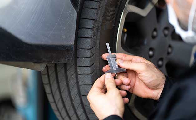 Mechanic checking checking the depth of car tire tread