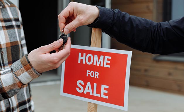 Agent handing over house keys in front of new home