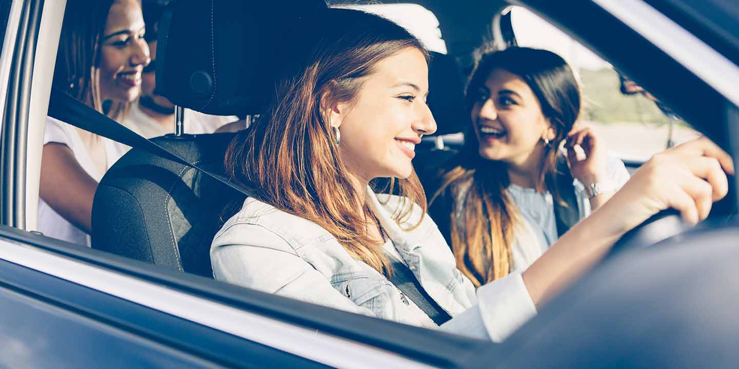 young woman driving a car with friends